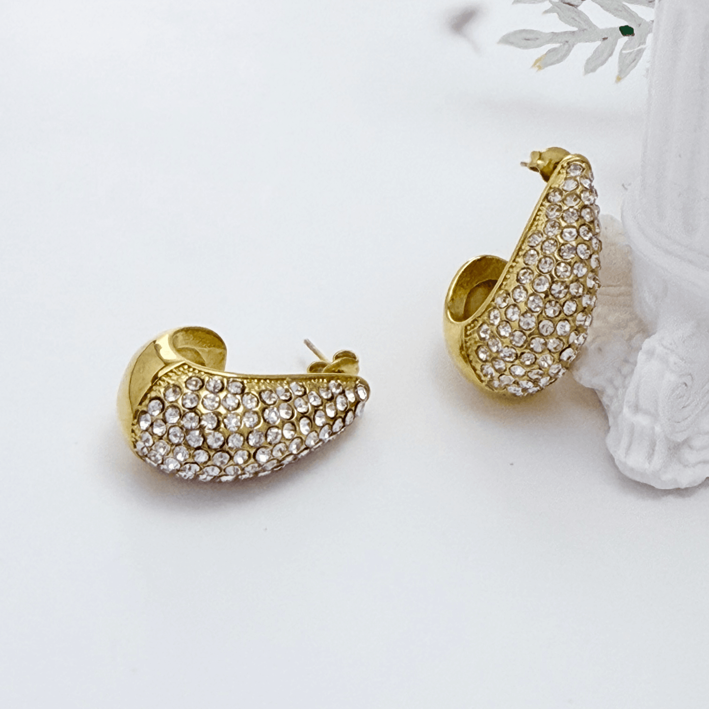 Chunky pavé gold half hoop earrings with crystal detailing, photographed on a clean light background.
