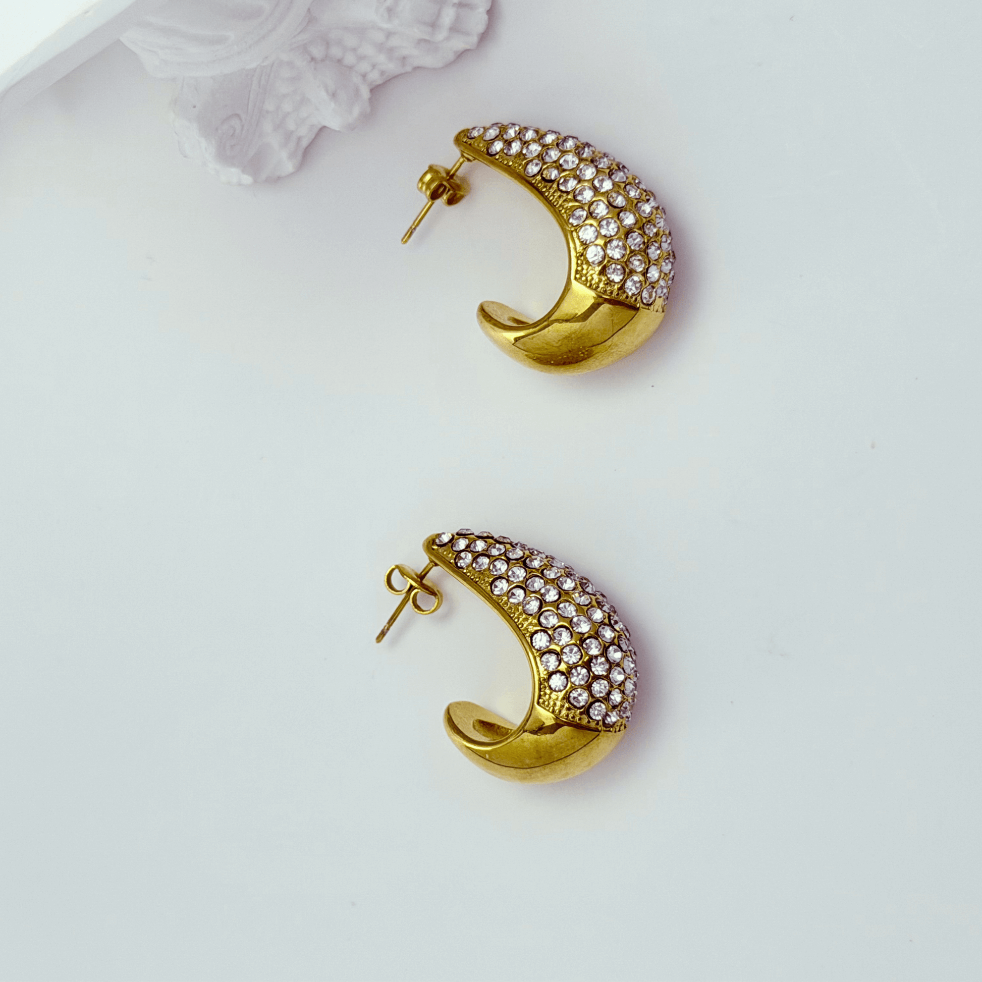 Chunky pavé gold half hoop earrings with crystal detailing, photographed on a clean light background.