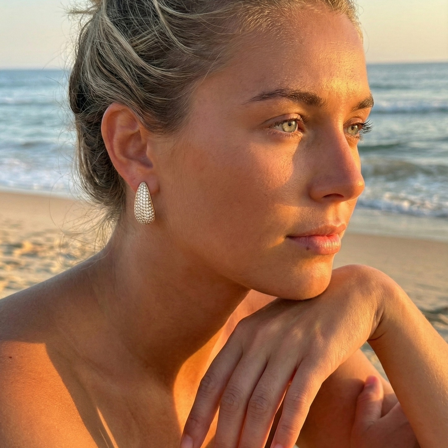 Chunky pavé gold half hoop earrings with crystal detailing, photographed on a clean light background.