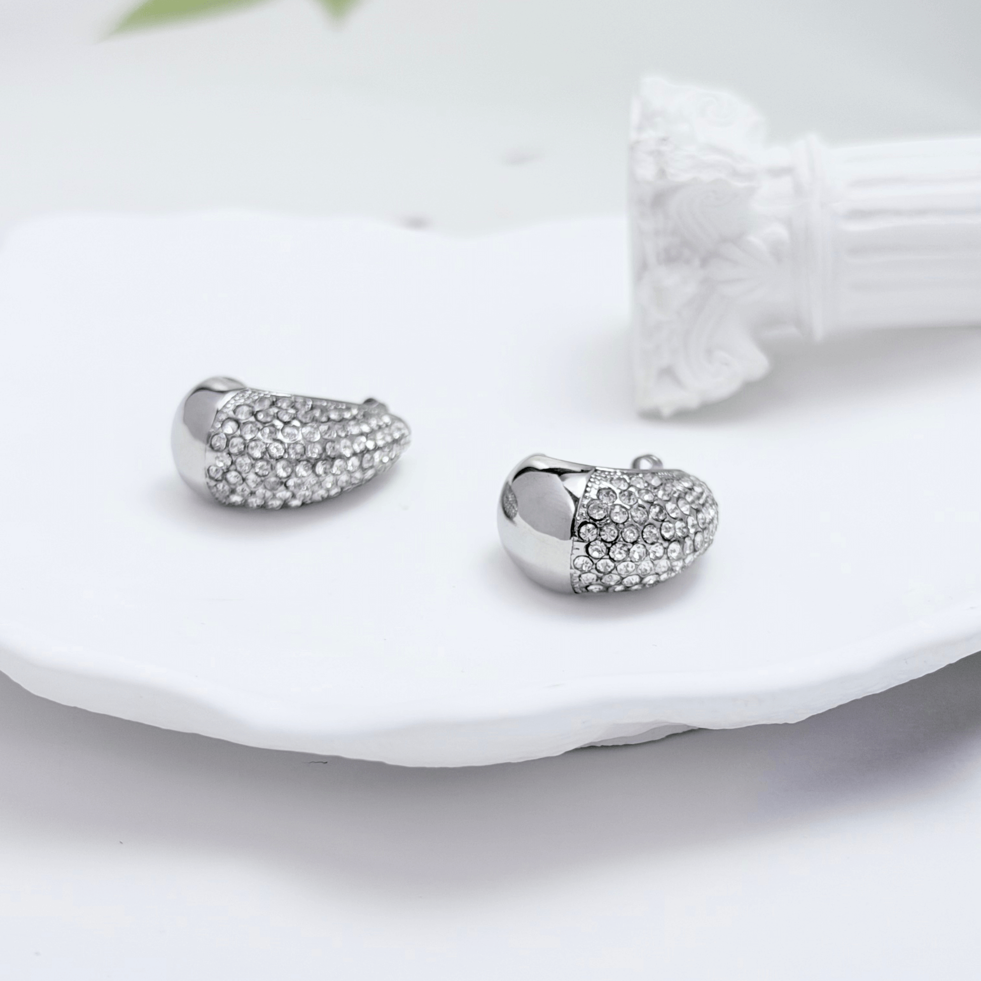 Chunky pavé silver half hoop earrings with crystal detailing, photographed on a light background.