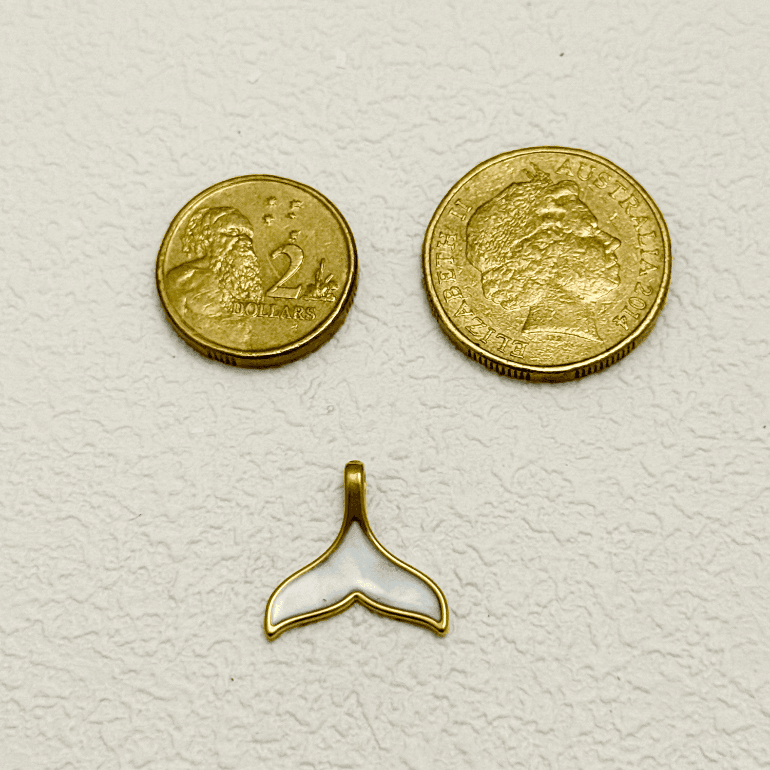 Gold and white enamel whale tail charm with smooth, glossy finish – nautical pendant