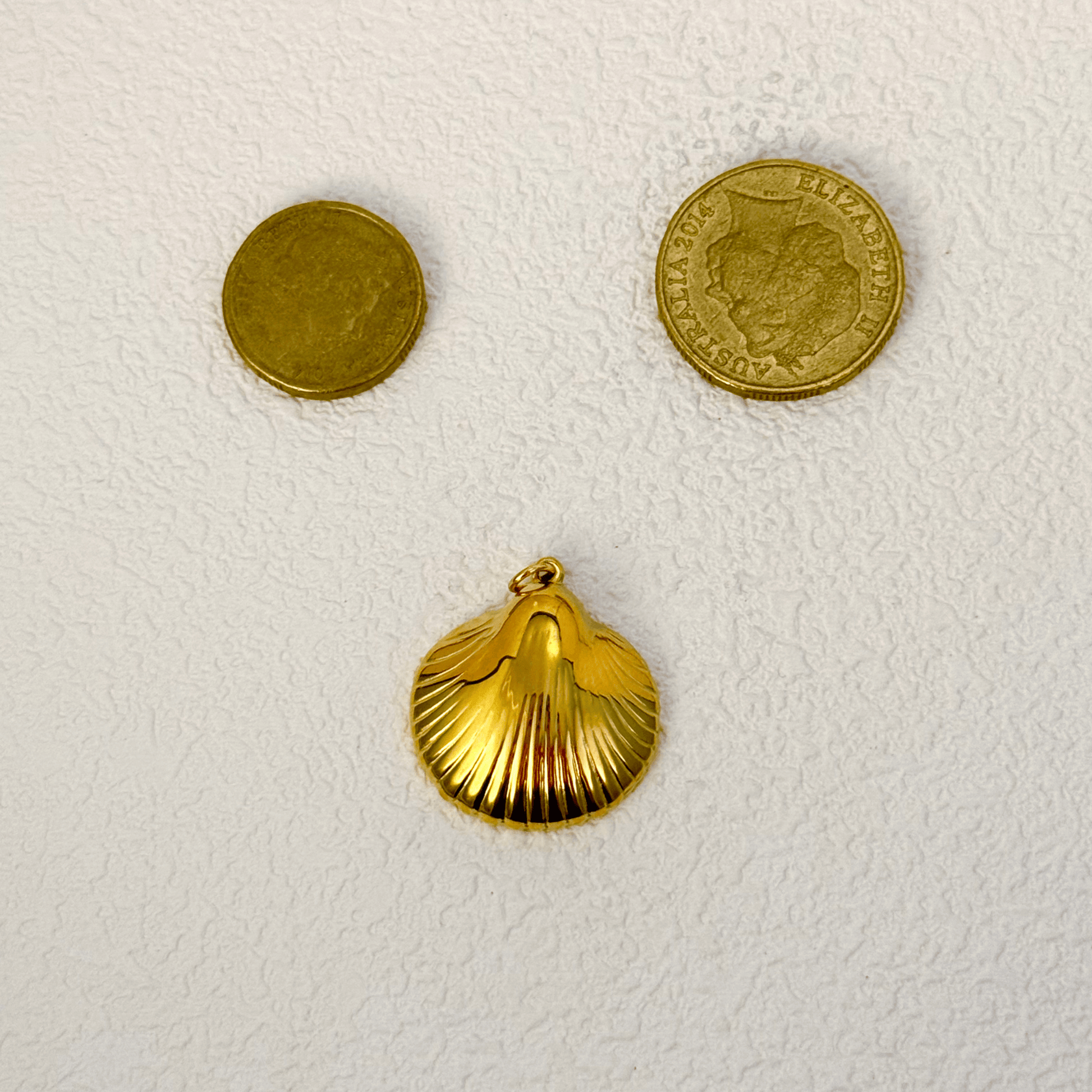 Smooth and polished gold shell charm in a scallop shape, inspired by sea treasures, perfect for beach or summer-themed jewelry.