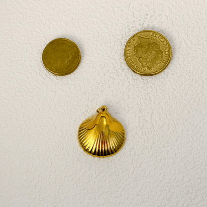 Smooth and polished gold shell charm in a scallop shape, inspired by sea treasures, perfect for beach or summer-themed jewelry.