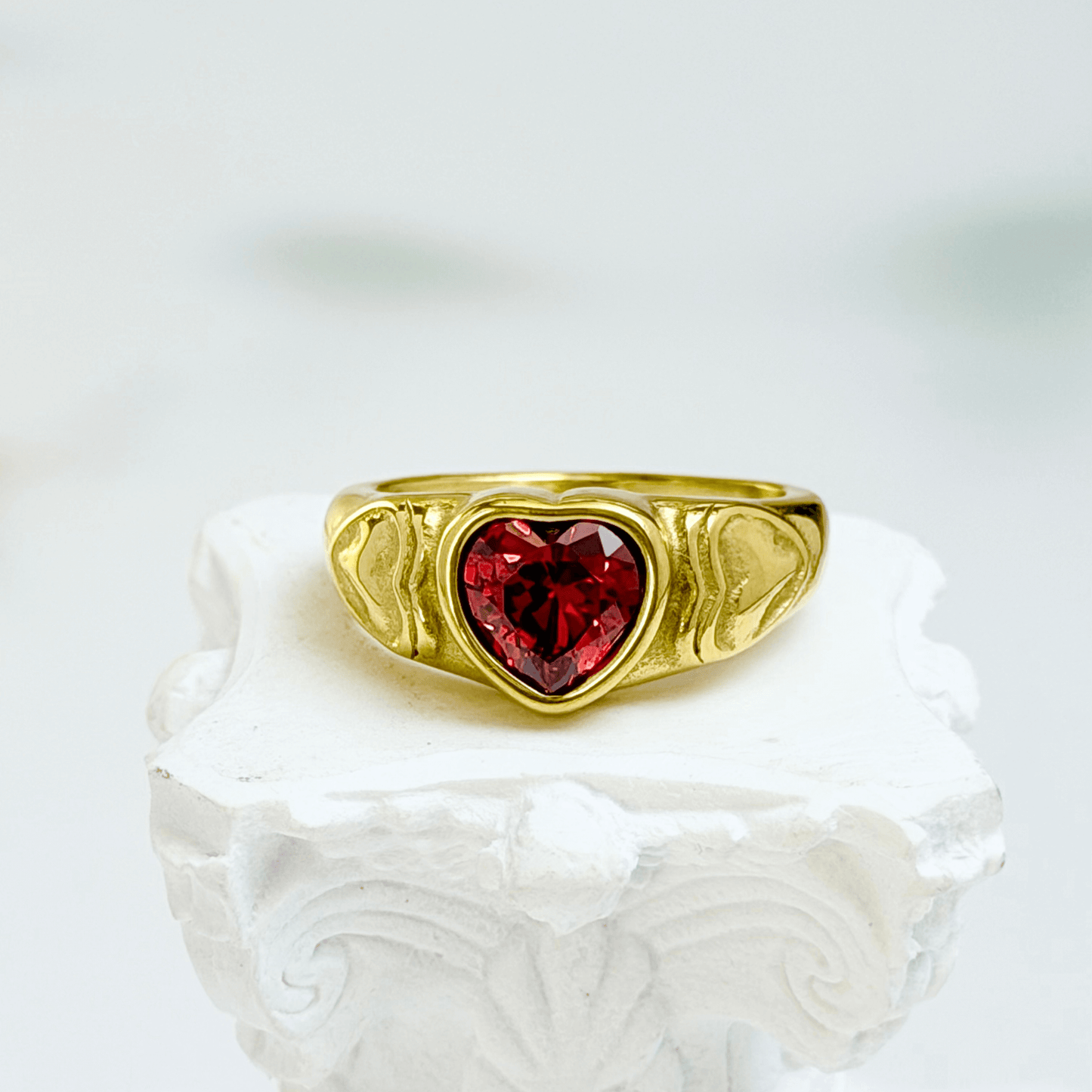 gold signet ring with a red heart-shaped stone in the centre