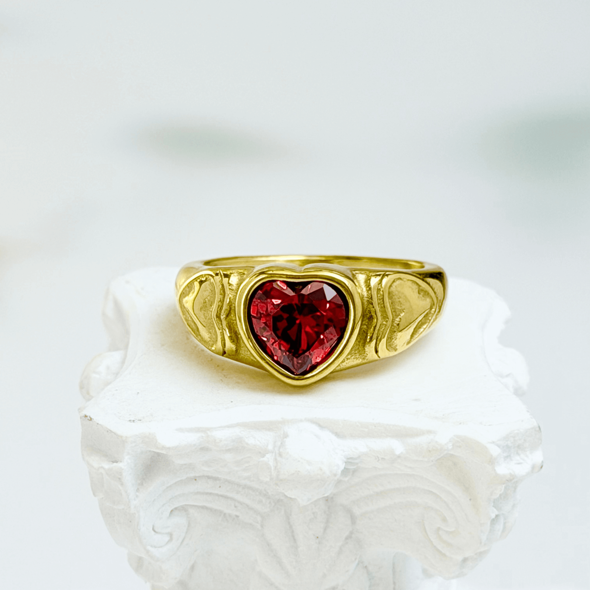 gold signet ring with a red heart-shaped stone in the centre