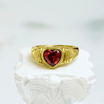 gold signet ring with a red heart-shaped stone in the centre