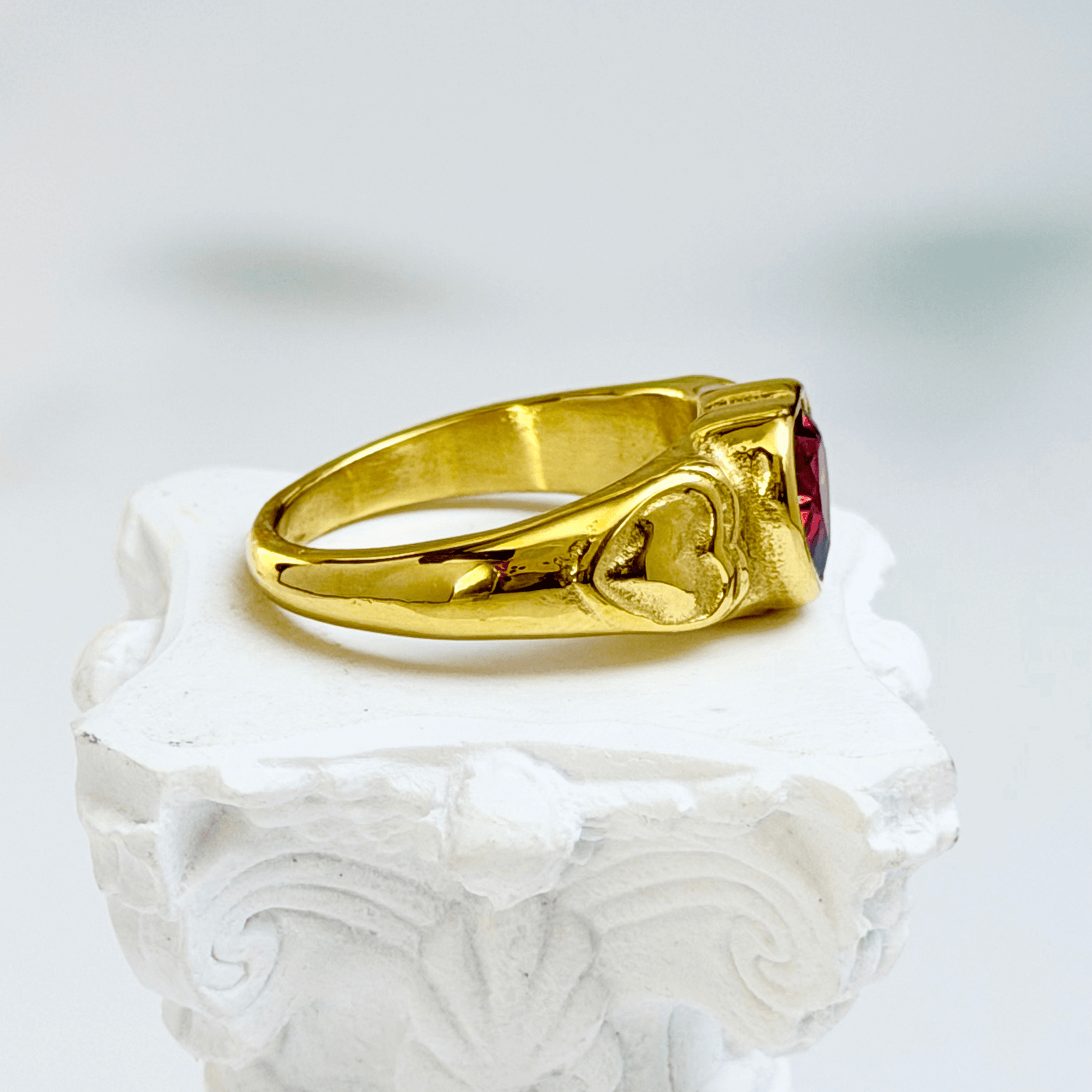 gold signet ring with a red heart-shaped stone in the centre