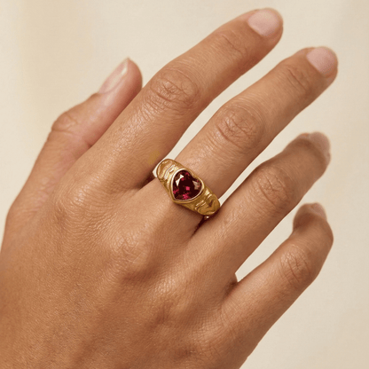 gold signet ring with a red heart-shaped stone in the centre