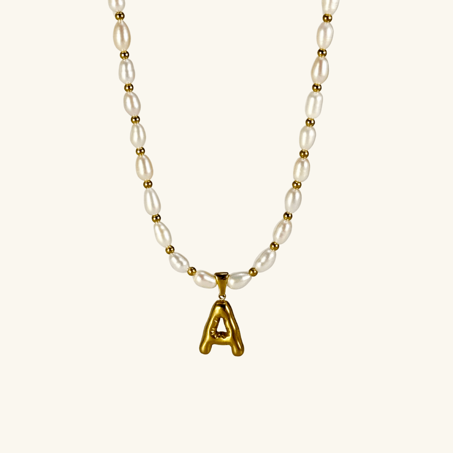 Custom freshwater pearl necklace with gold bubble initial pendant on display stand