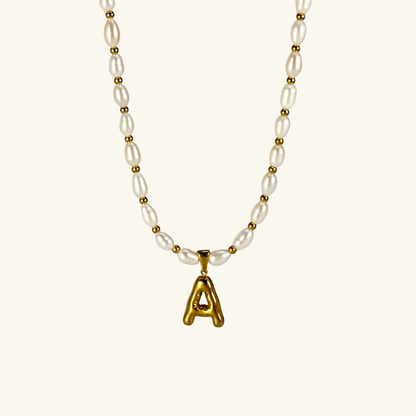 Custom freshwater pearl necklace with gold bubble initial pendant on display stand