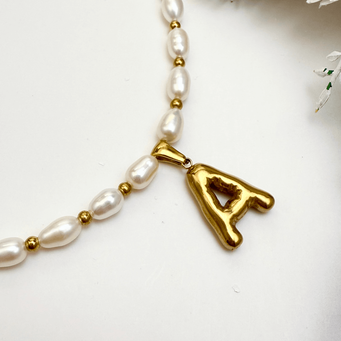 Custom freshwater pearl necklace with gold bubble initial pendant on display stand