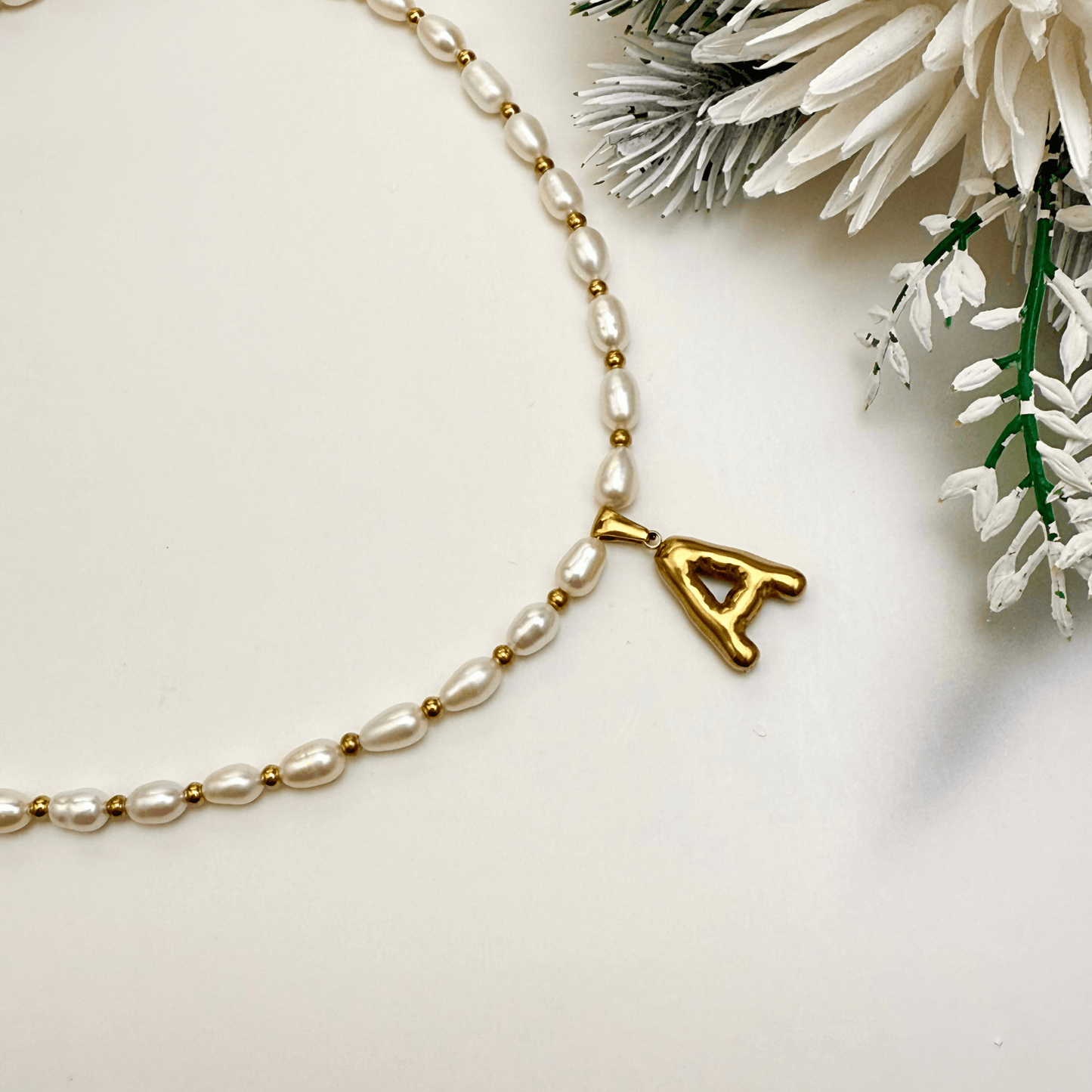 Custom freshwater pearl necklace with gold bubble initial pendant on display stand