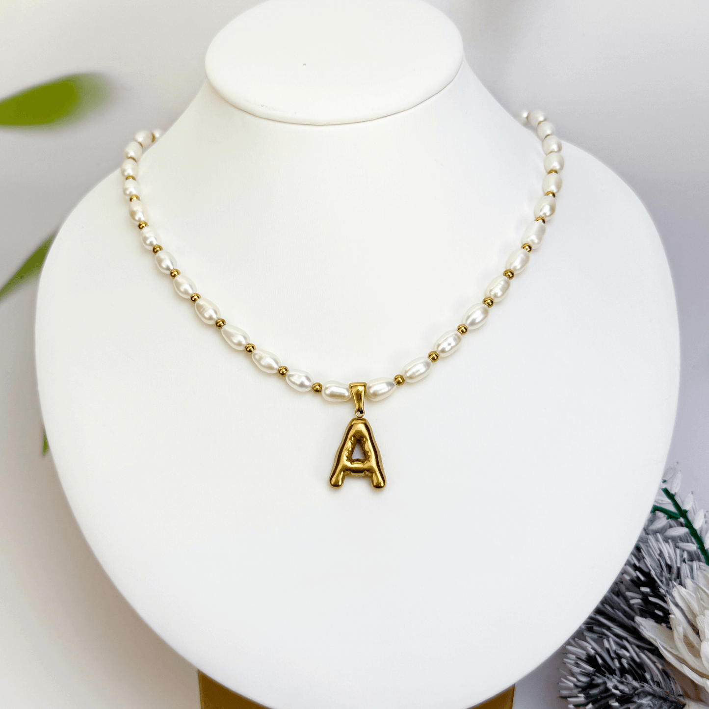 Custom freshwater pearl necklace with gold bubble initial pendant on display stand