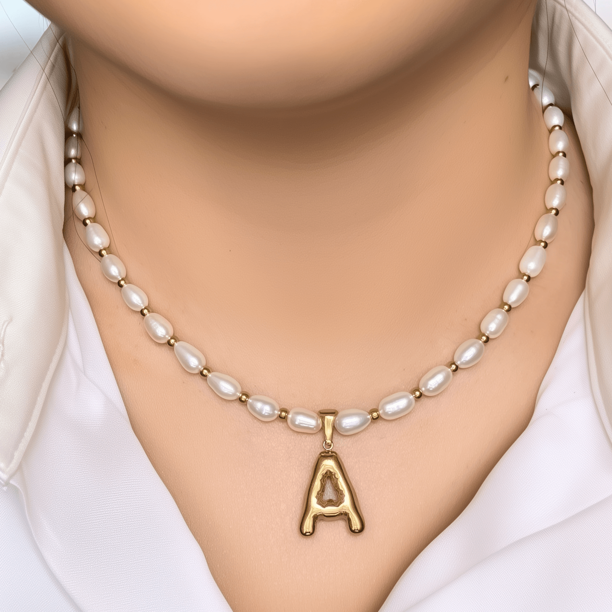 Custom freshwater pearl necklace with gold bubble initial pendant on display stand
