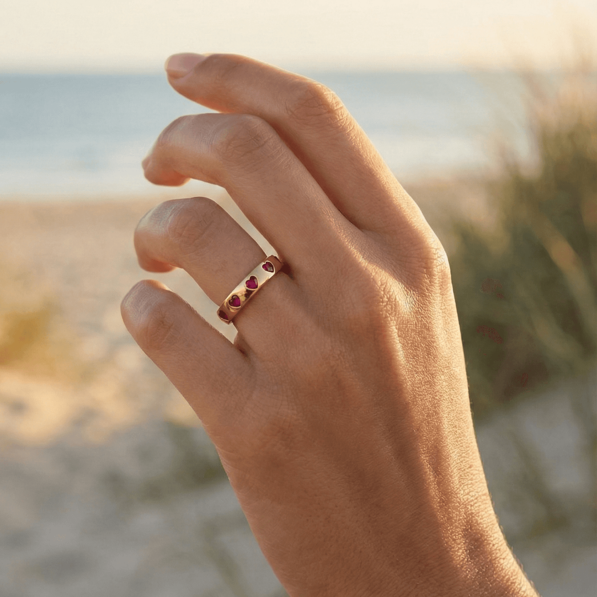 Gold waterproof ring with alternating pink and clear heart-shaped stones.