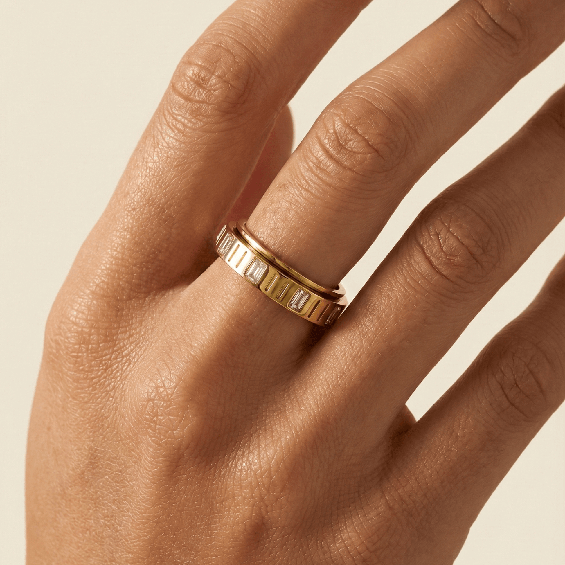 Gold Baguette Spinner Ring by MXW Jewellery featuring a rotating band set with clear rectangular crystals.