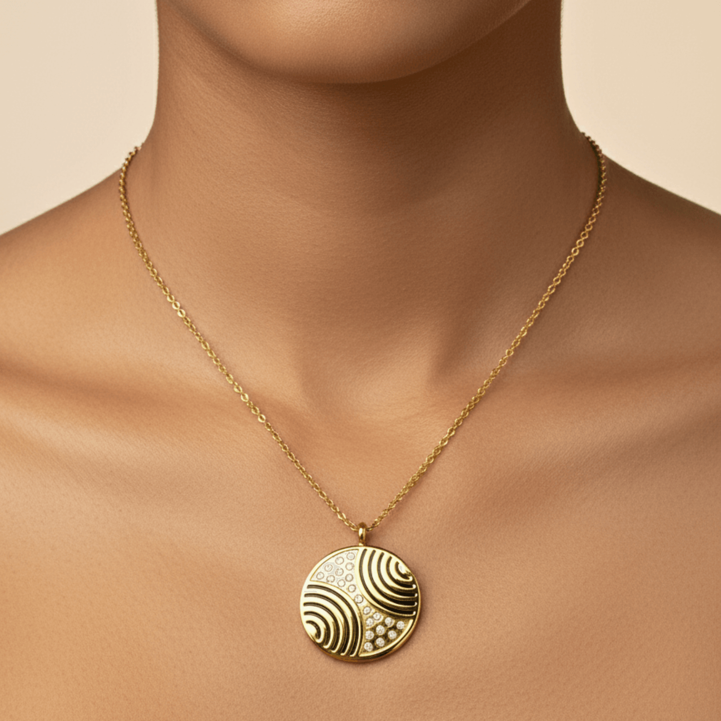 Gold round pendant necklace with engraved flowing pattern and crystal detailing, symbolising harmony and balance.