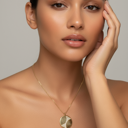 Gold round pendant necklace with engraved flowing pattern and crystal detailing, symbolising harmony and balance.