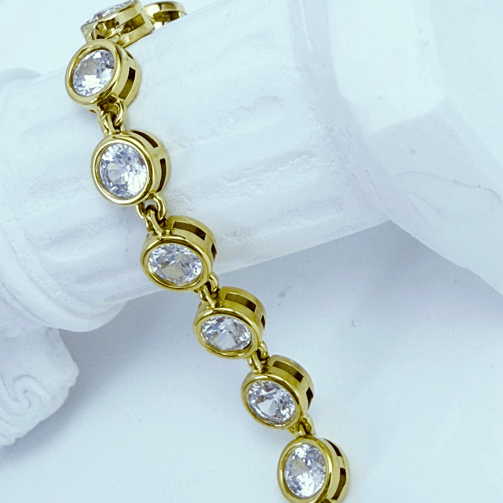 Gold crystal tennis bracelet with bezel-set clear stones.