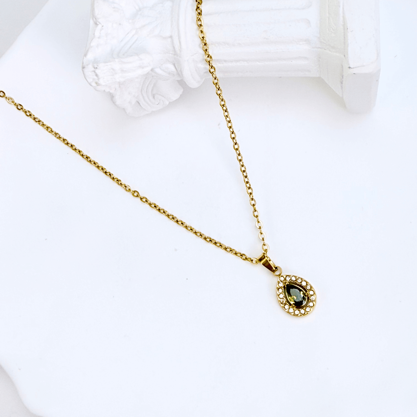 gold emerald glow teardrop necklace with green gemstone surrounded by clear crystals on gold chain