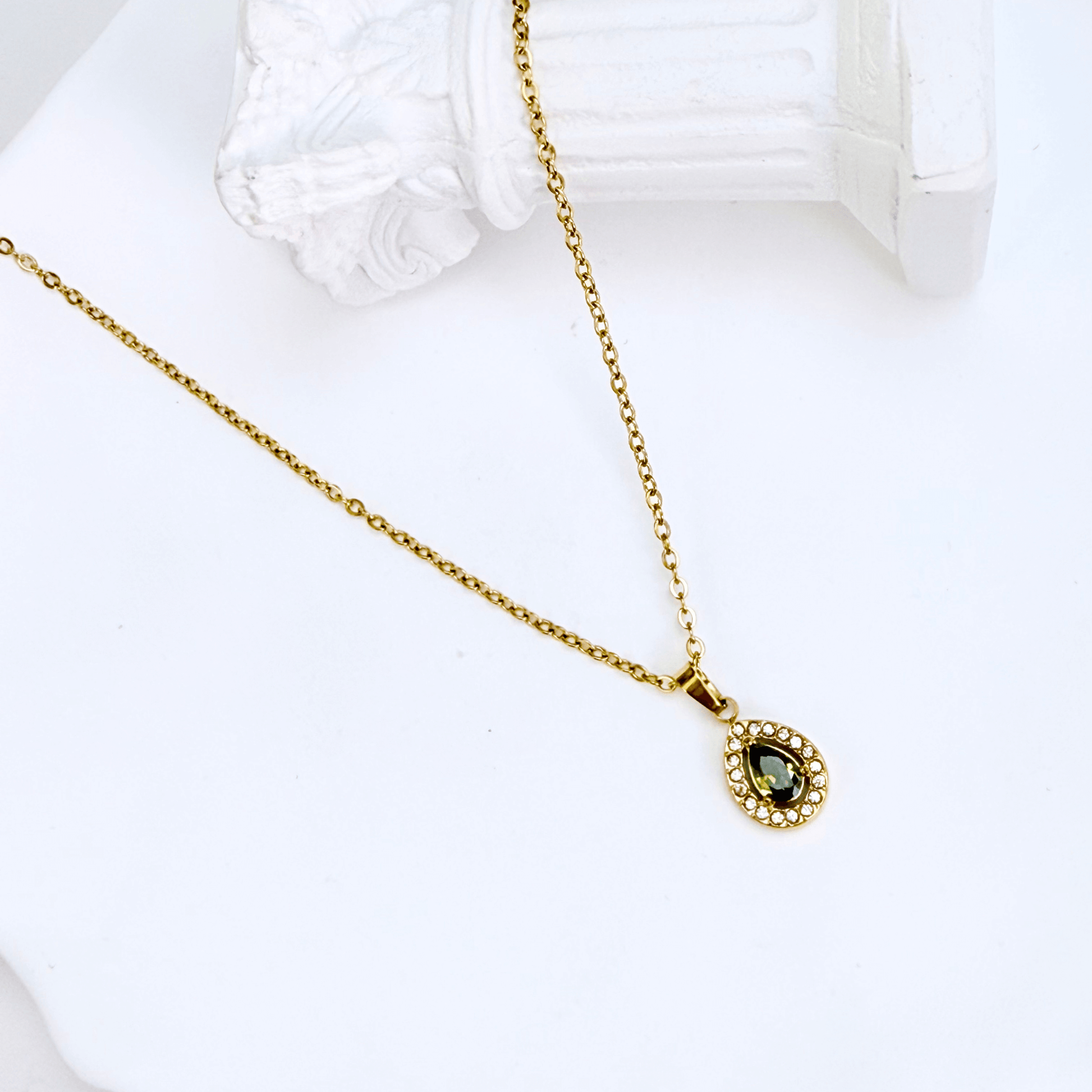 gold emerald glow teardrop necklace with green gemstone surrounded by clear crystals on gold chain