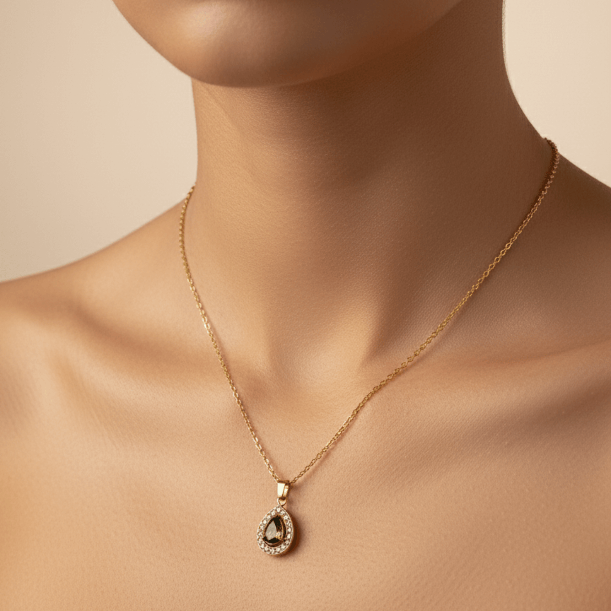 gold emerald glow teardrop necklace with green gemstone surrounded by clear crystals on gold chain