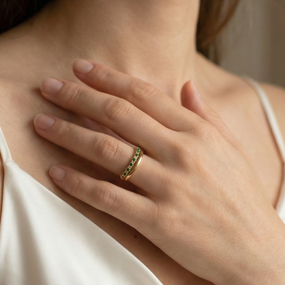Gold curved stacking ring with emerald green crystals on white pedestal MXW Jewellery