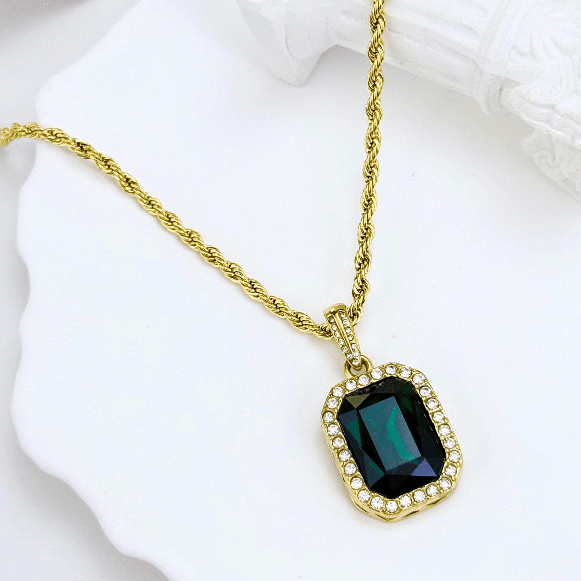 Gold emerald halo necklace featuring rectangular green zircon pendant on gold rope chain.