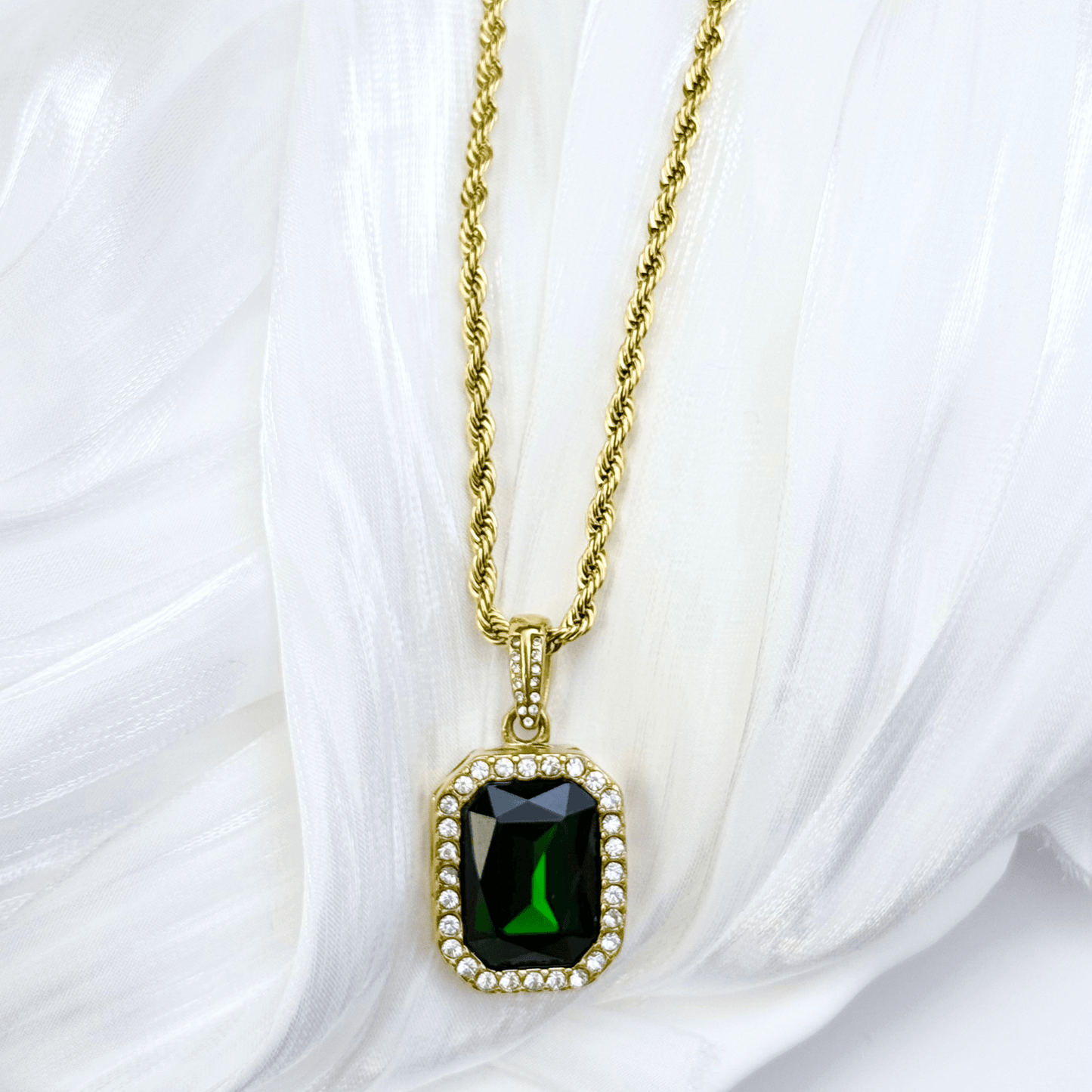 Gold emerald halo necklace featuring rectangular green zircon pendant on gold rope chain.