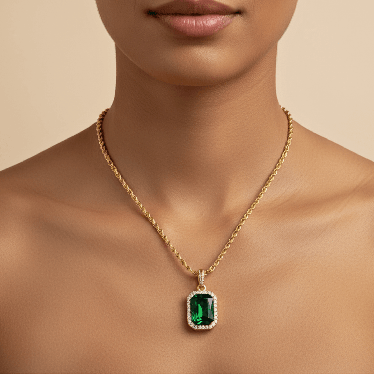 Gold emerald halo necklace featuring rectangular green zircon pendant on gold rope chain.
