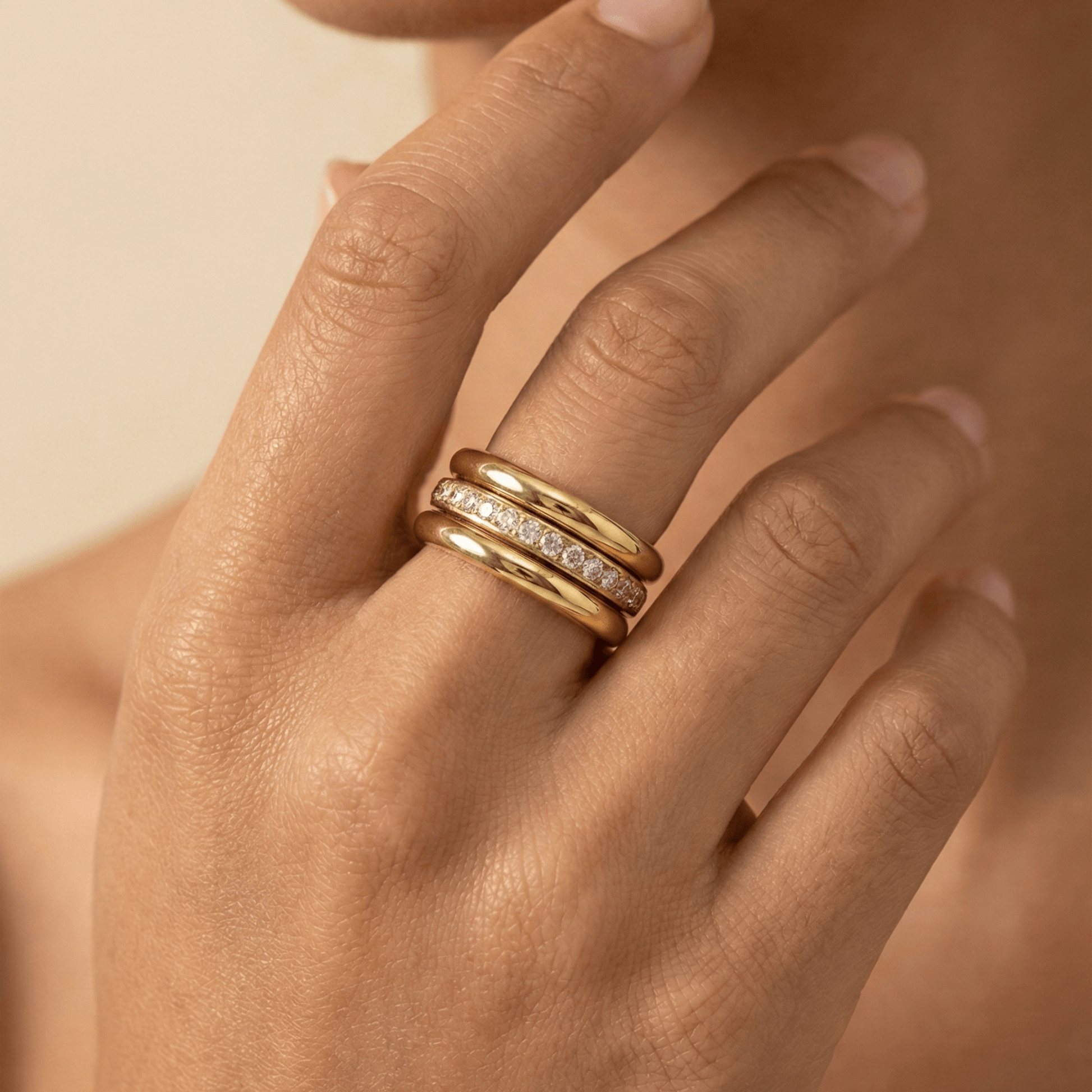 Close up of Gold Eternity Trio Stacking Ring Set by MXW Jewellery featuring a central crystal band nestled between two smooth gold bands.