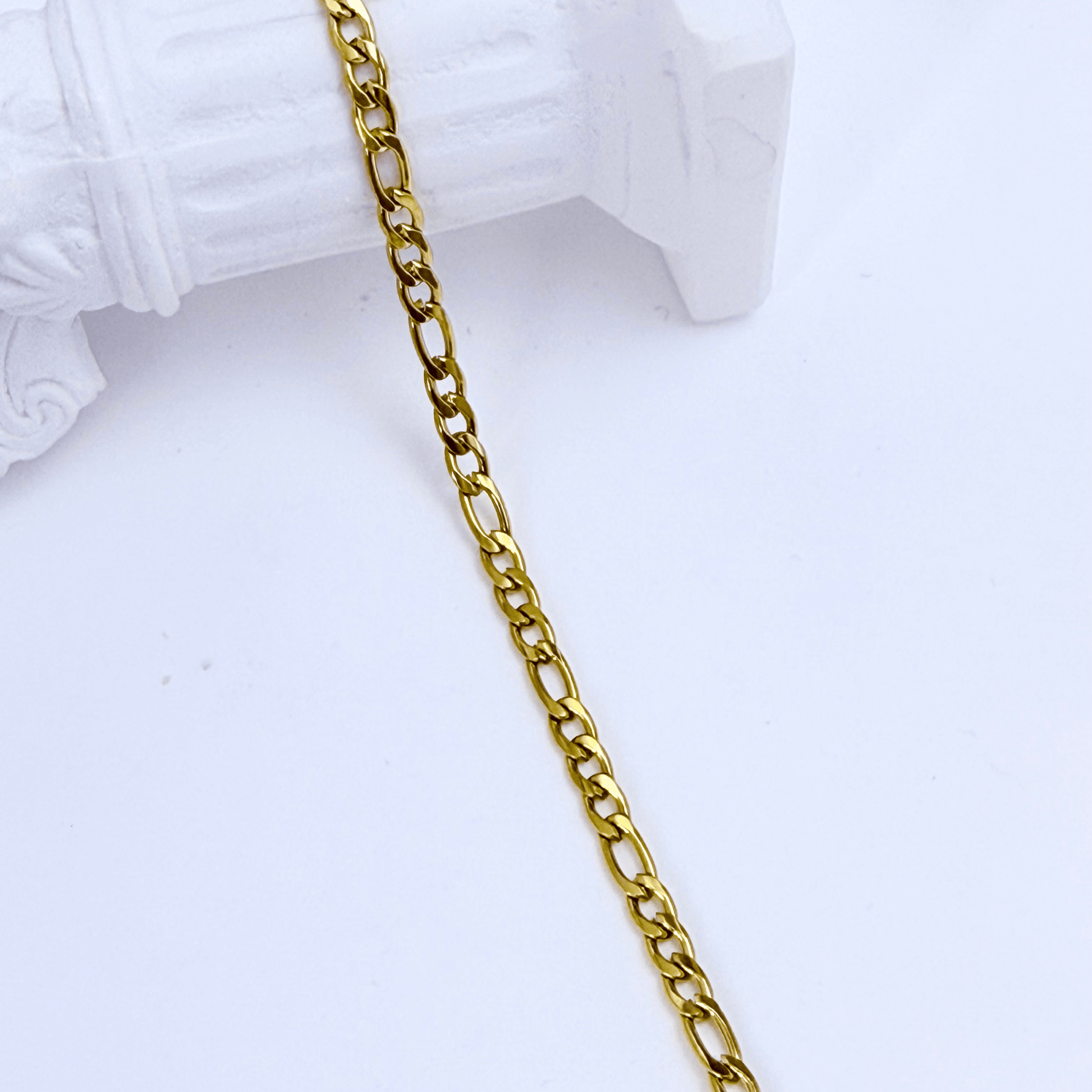 Gold Figaro link chain bracelet with polished elongated and short links.