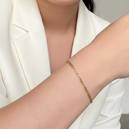 Gold Figaro link chain bracelet with polished elongated and short links.