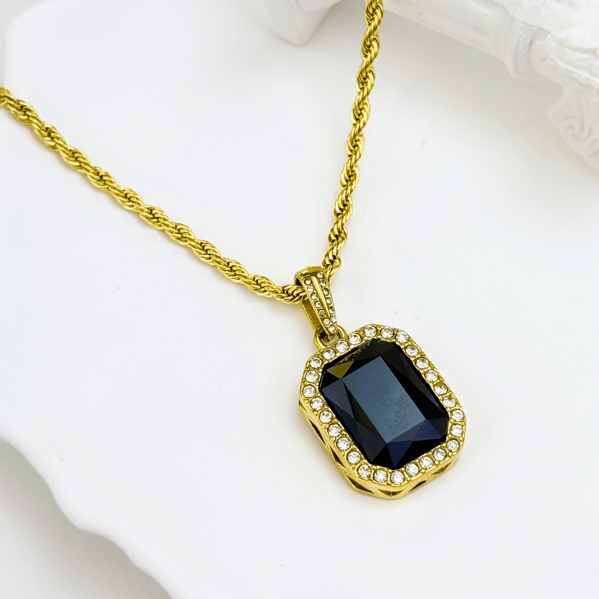 Gold onyx halo necklace with rectangular black zircon pendant and crystal halo on gold rope chain.