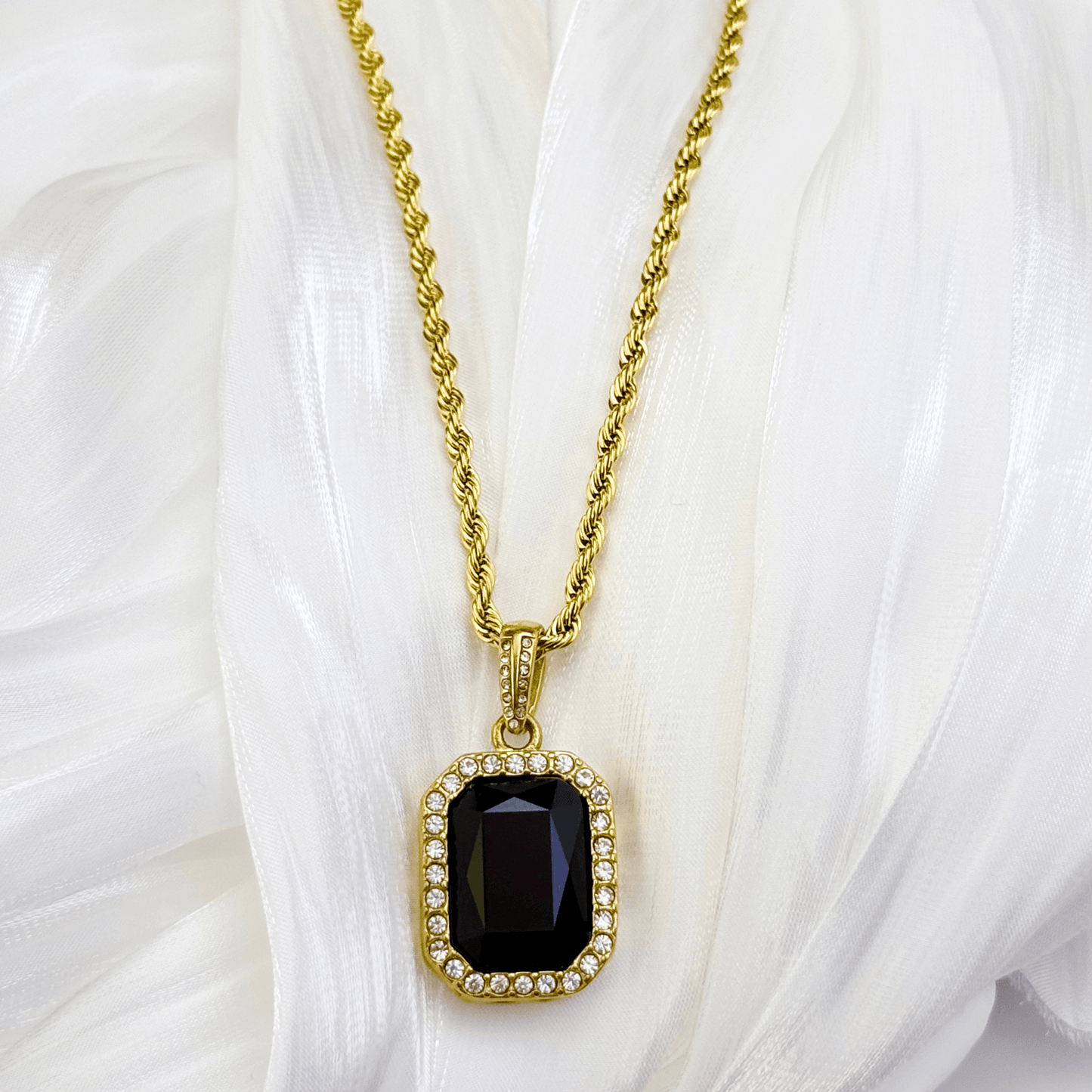 Gold onyx halo necklace with rectangular black zircon pendant and crystal halo on gold rope chain.