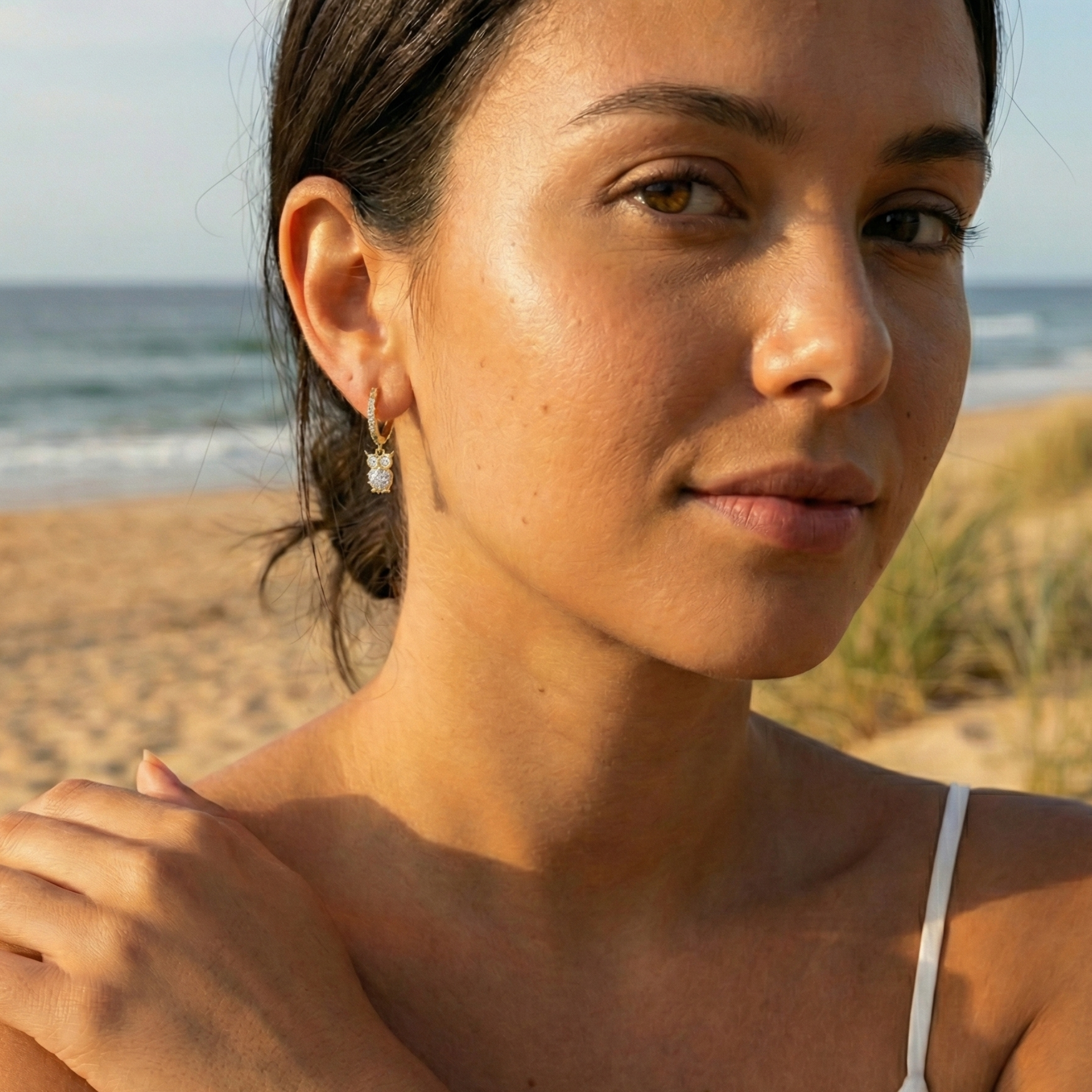 Gold huggie hoop earrings featuring a dangling crystal owl charm with a large solitaire body stone by MXW Jewellery