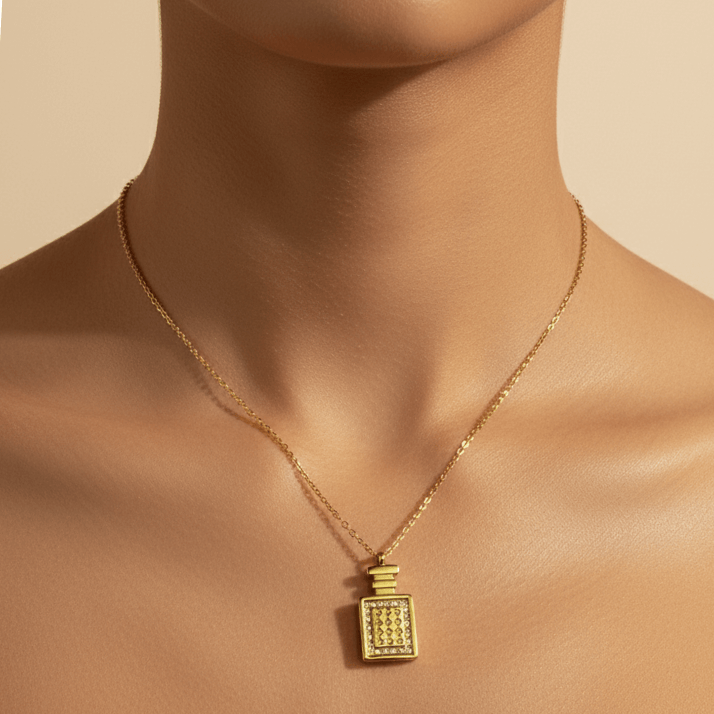 Gold perfume bottle pendant necklace with crystal detailing, symbolising elegance and charm.