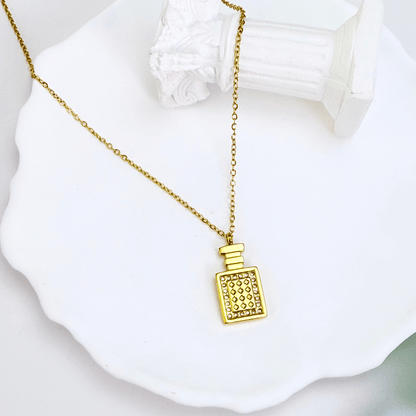 Gold perfume bottle pendant necklace with crystal detailing, symbolising elegance and charm.