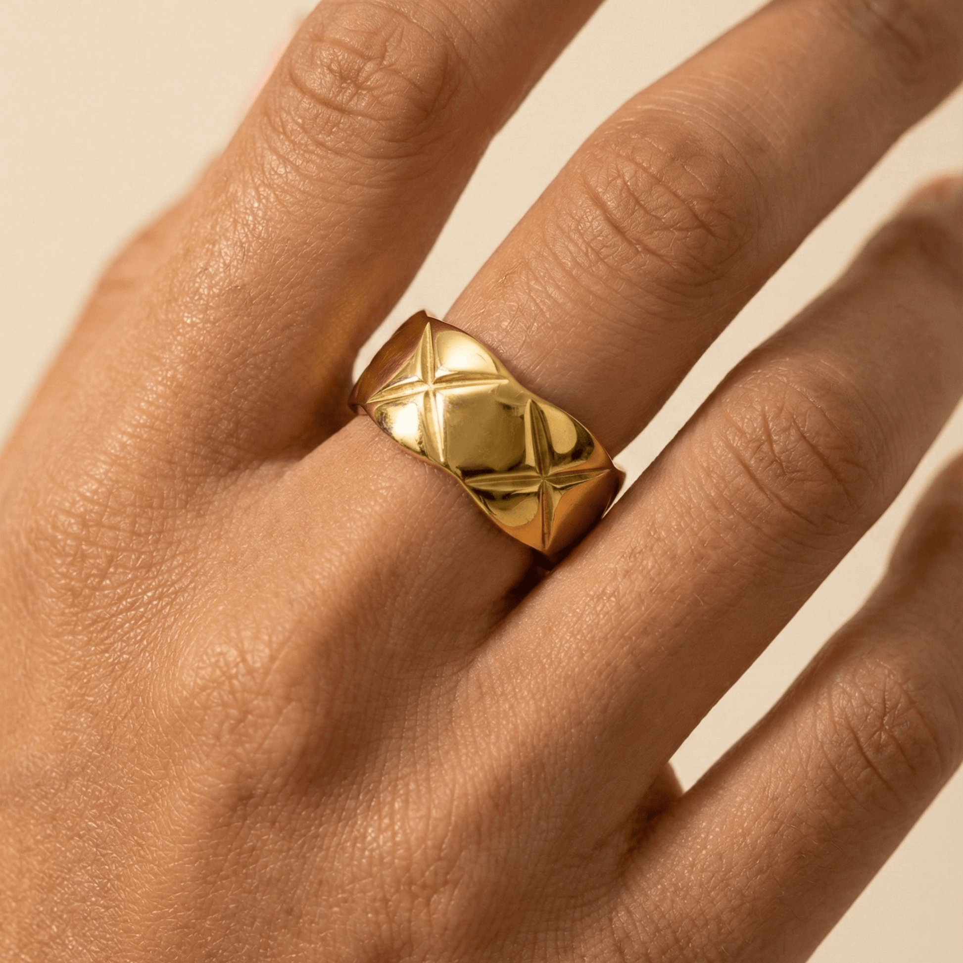 Quilted Gold Band Ring by MXW Jewellery, featuring a wide gold band with a geometric cross-hatch pattern on a white pedestal.