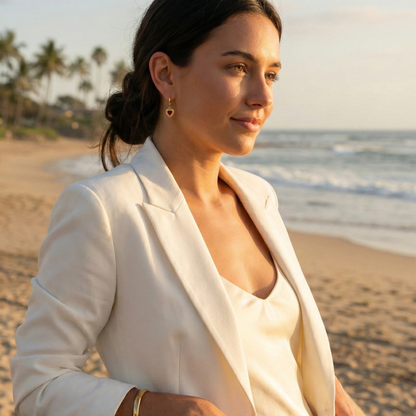 Gold hoop earrings featuring a textured heart charm with a red agate stone centre