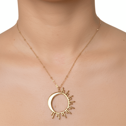 Waterproof gold solar eclipse necklace featuring a crescent moon overlapping a radiant sunburst design on a fine beaded chain, made with PVD gold plated stainless steel.
