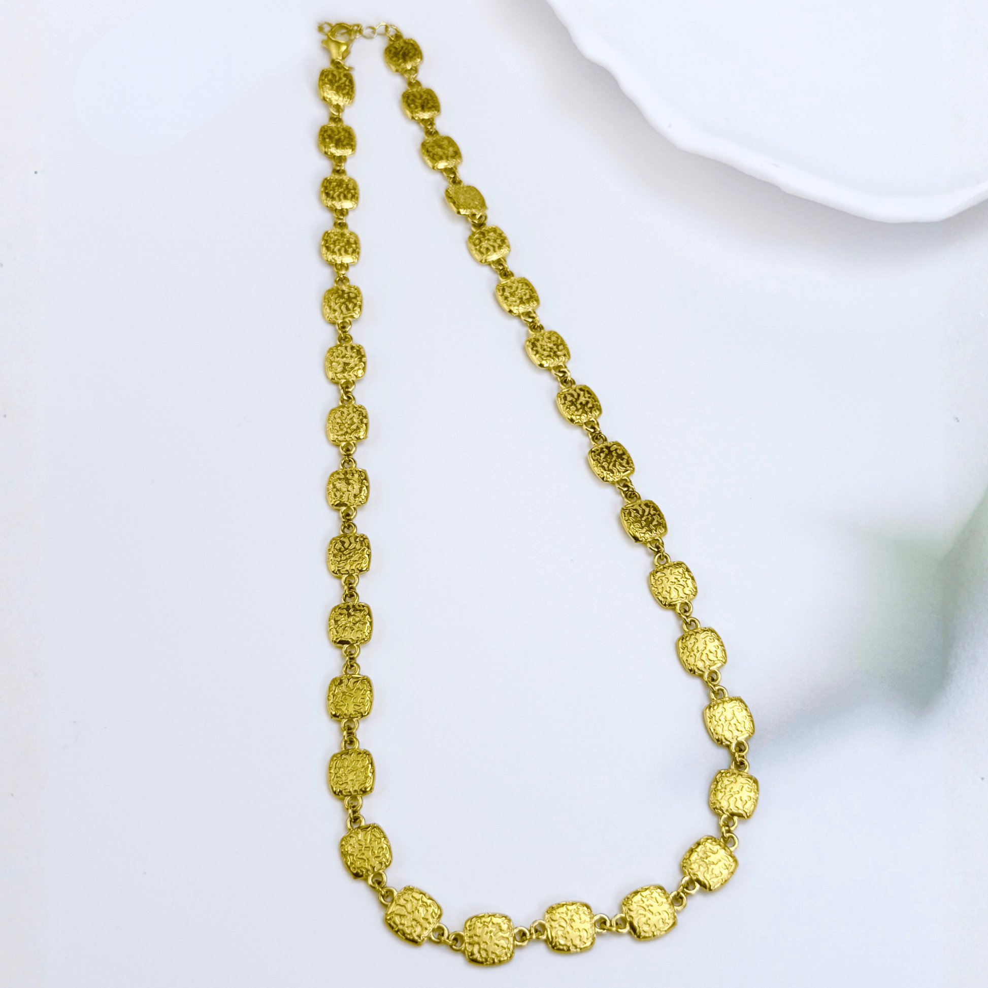 Gold textured square link chain necklace featuring small engraved square links connected in a continuous gold pattern.