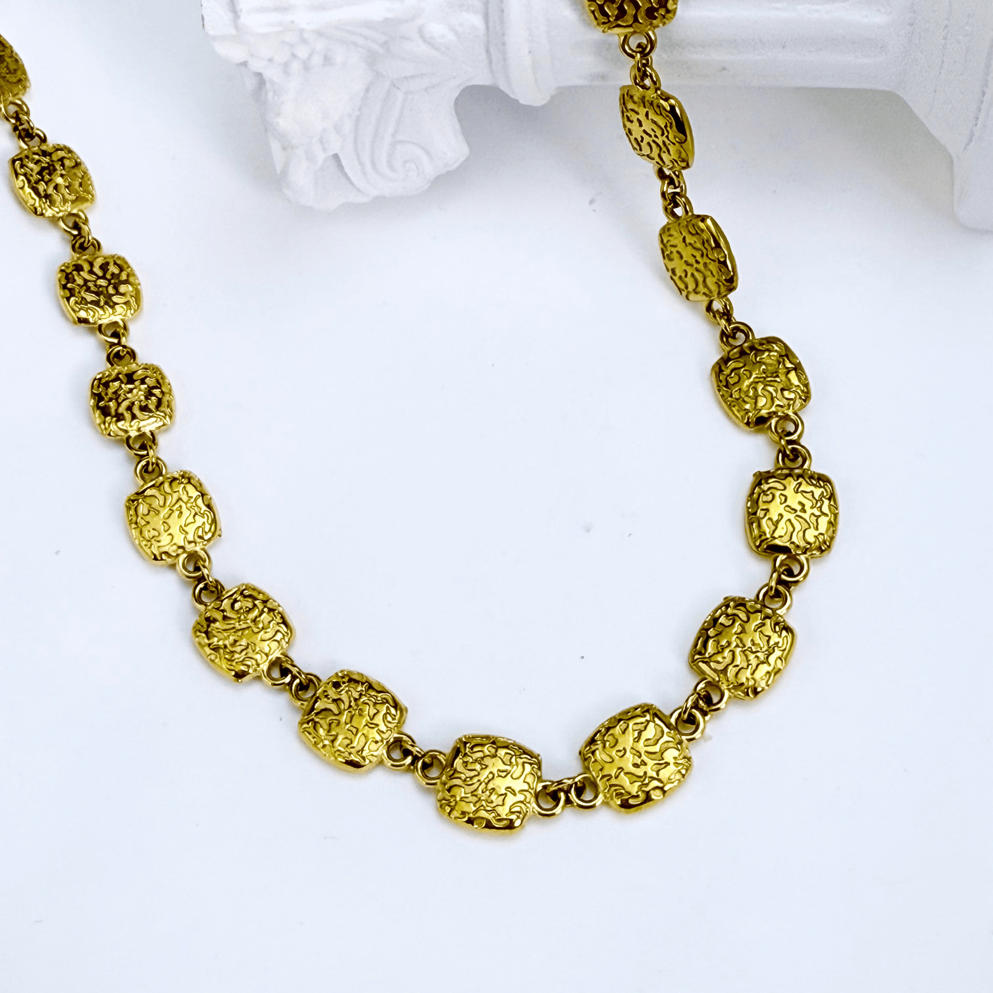 Gold textured square link chain necklace featuring small engraved square links connected in a continuous gold pattern.