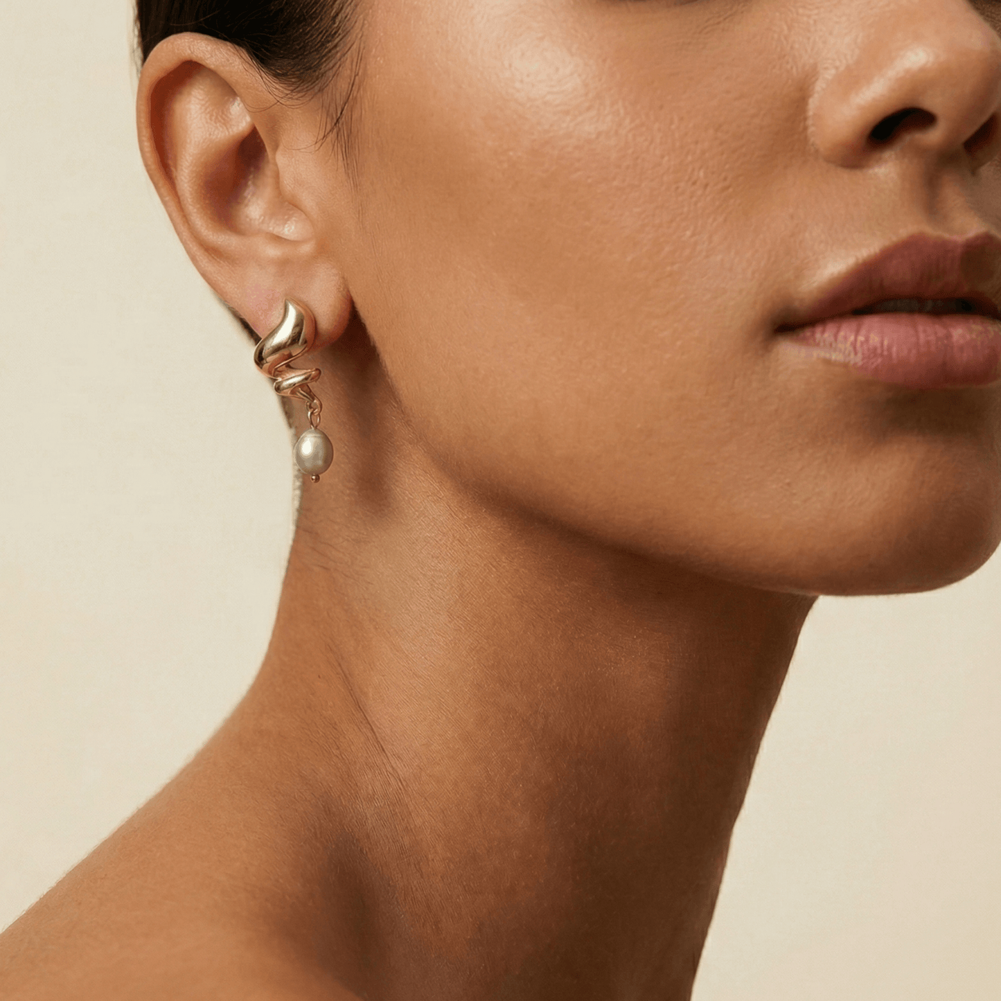 Gold twisted swirl pearl drop earrings displayed on a white bust, minimalist Australian design by MXW Jewellery