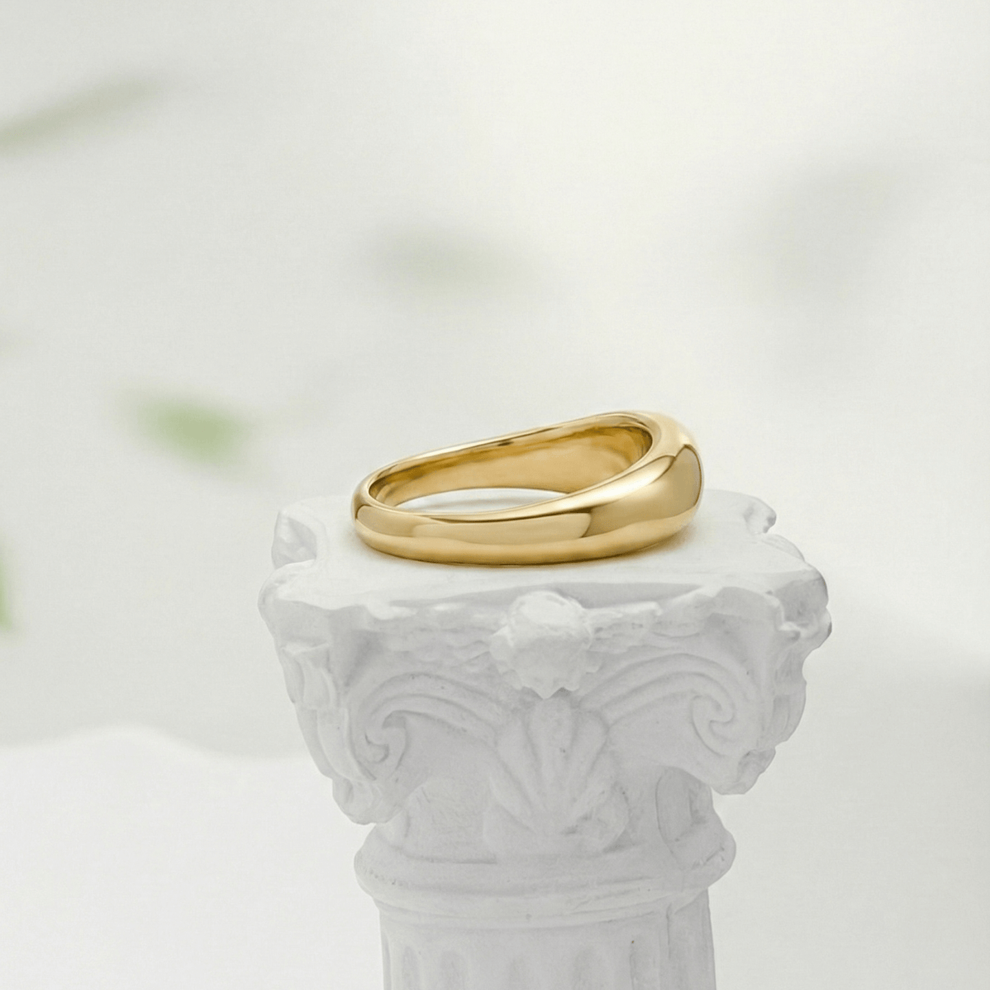 Gold Wave Ring by MXW Jewellery featuring a sculptural fluid design and waterproof gold finish displayed on a white textured column