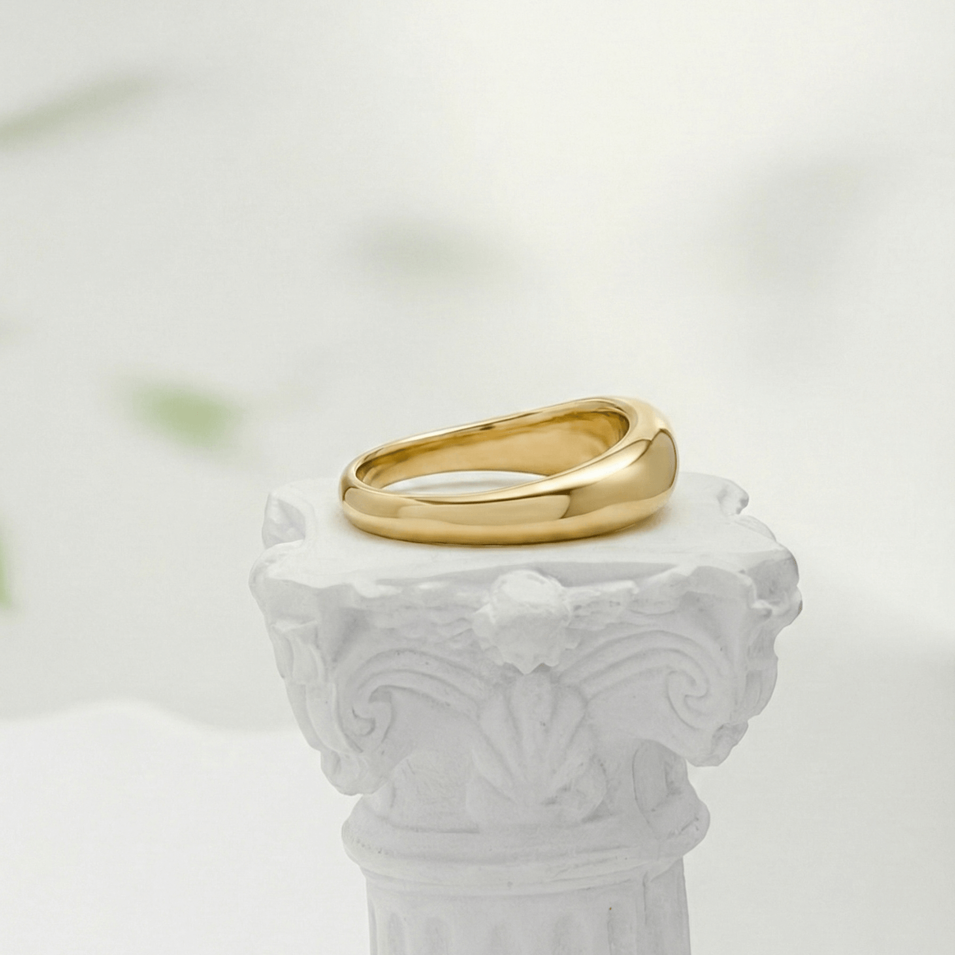 Gold Wave Ring by MXW Jewellery featuring a sculptural fluid design and waterproof gold finish displayed on a white textured column