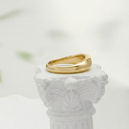 Gold Wave Ring by MXW Jewellery featuring a sculptural fluid design and waterproof gold finish displayed on a white textured column
