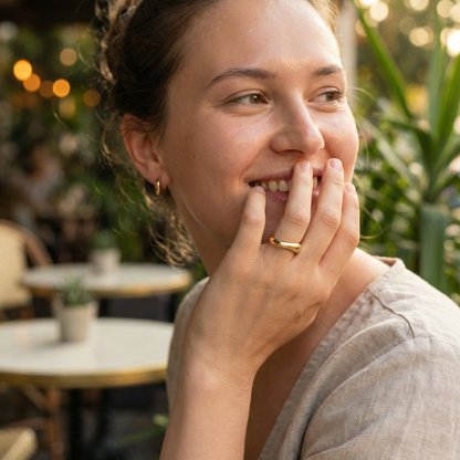 Gold Wave Ring by MXW Jewellery featuring a sculptural fluid design and waterproof gold finish displayed on a white textured column