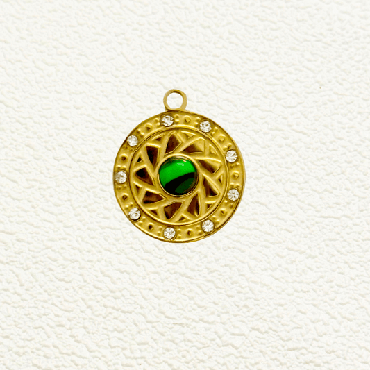 Gold round sun charm with green enamel center and crystal border, intricate celestial design.