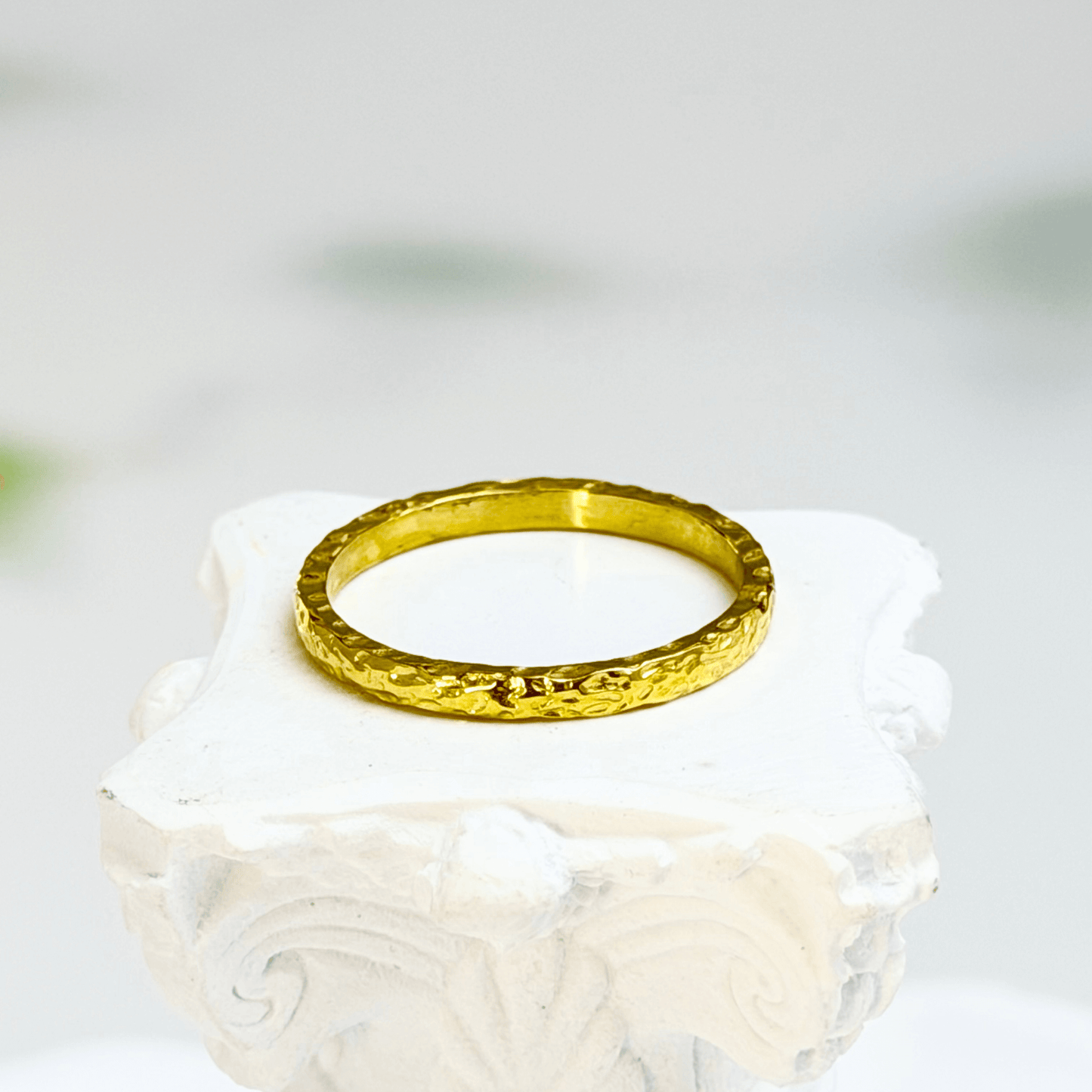 Minimal hammered slim gold ring with organic texture on a clean background.